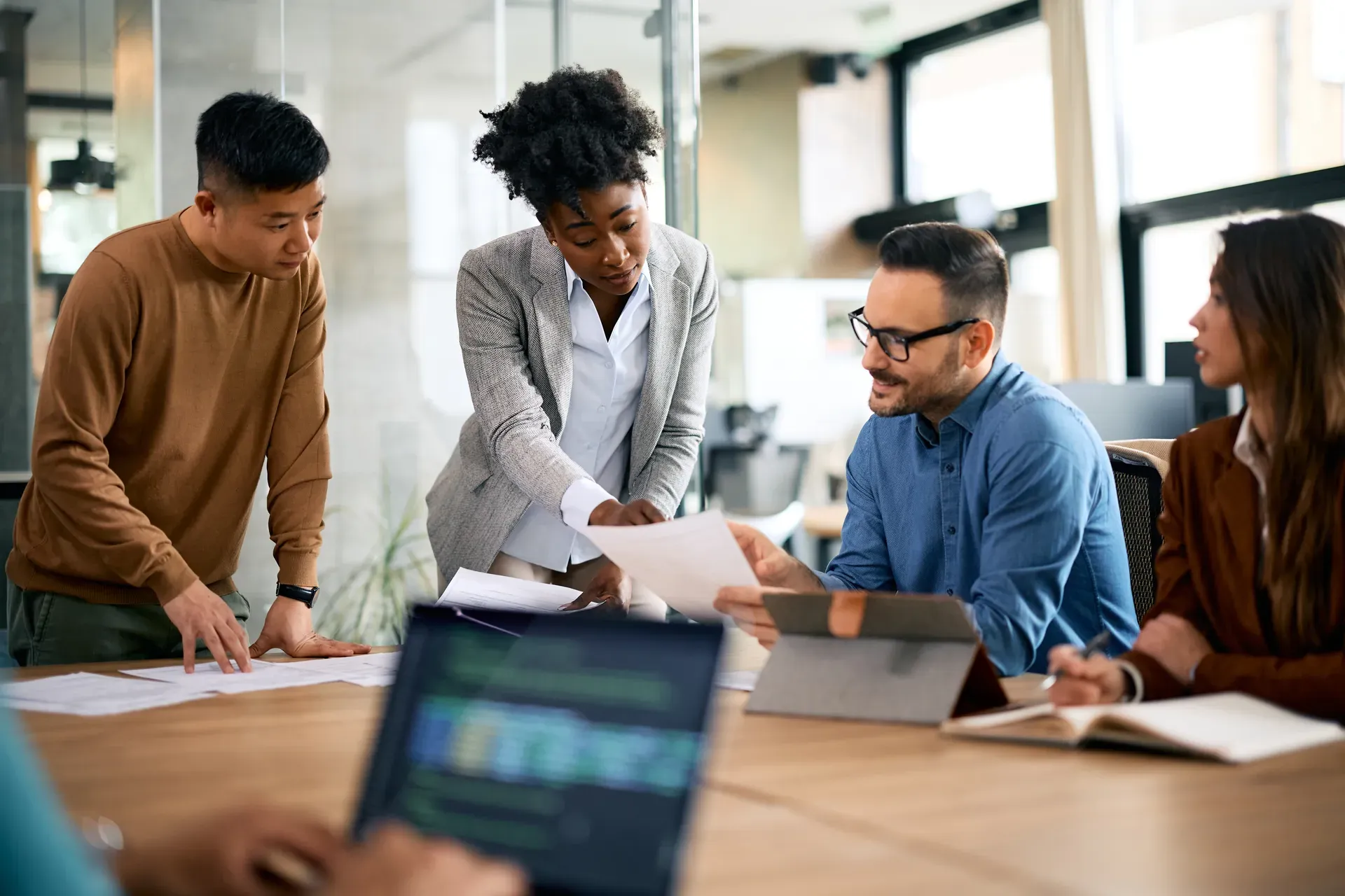 Team am Besprechungstisch analysiert gemeinsam Berichte auf Papier und Tablet